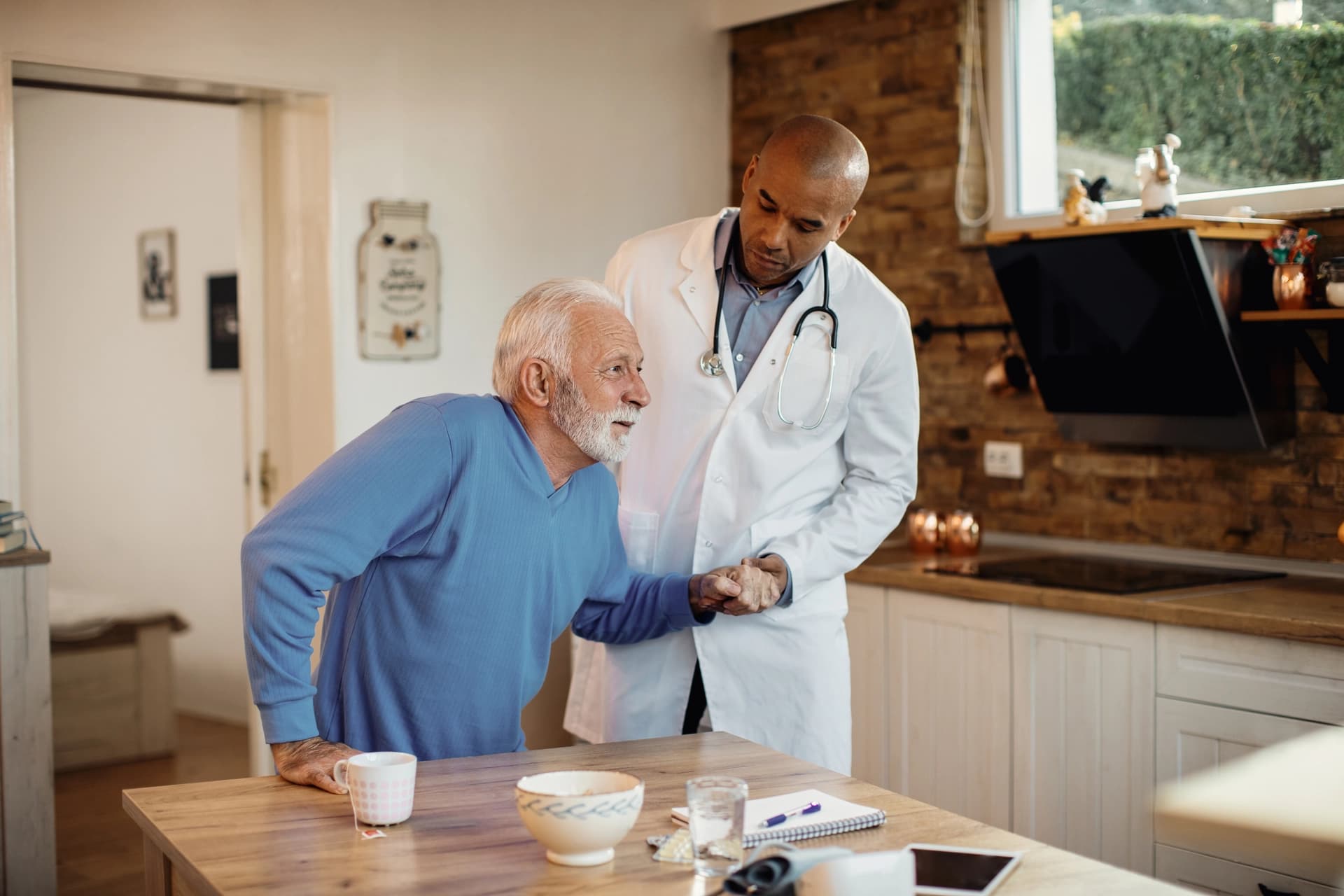 A male social worker supporting an older woman