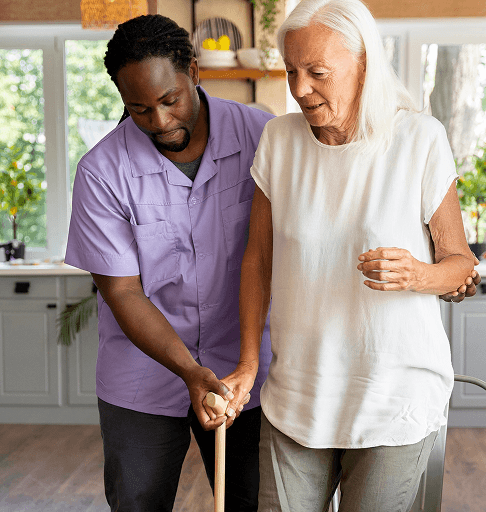 A support worker helping an older woman move safely at home
